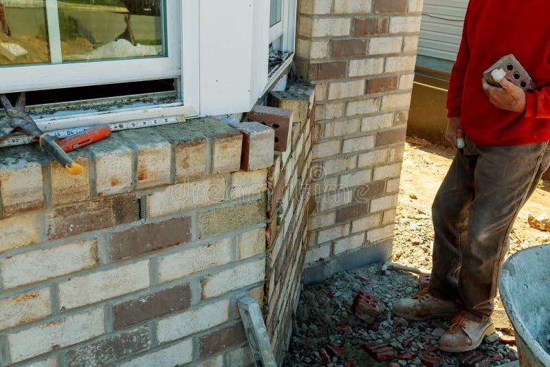 Construction Workers Laying Clay Brick To Form Brick Wall at the