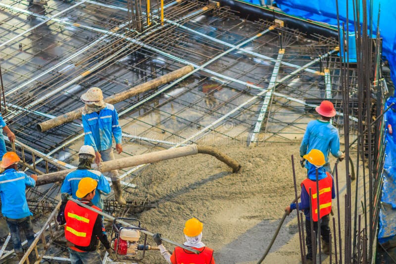 Construction workers are pouring concrete in post-tension flooring work. Mason workers carrying hose from concrete pump or also k stock photos