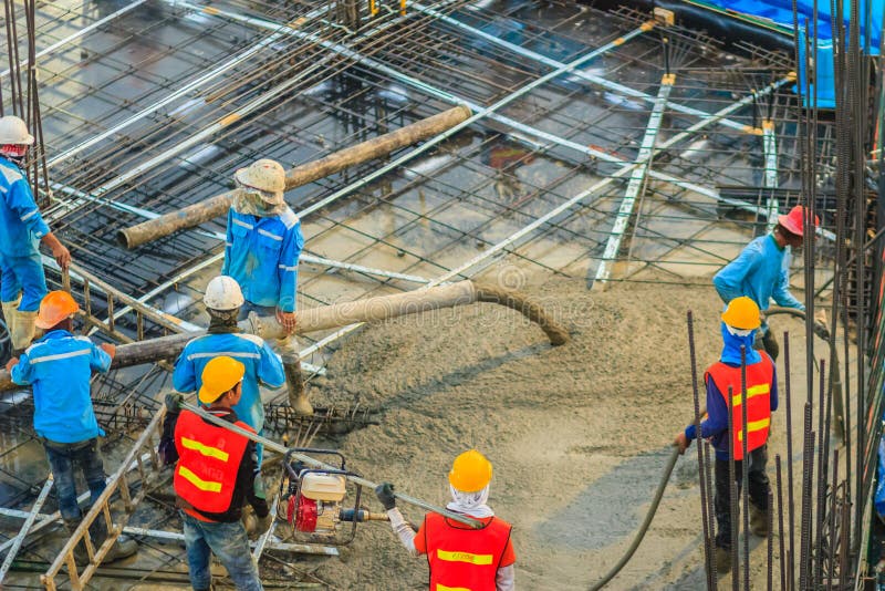 Construction workers are pouring concrete in post-tension flooring work. Mason workers carrying hose from concrete pump or also k stock photo