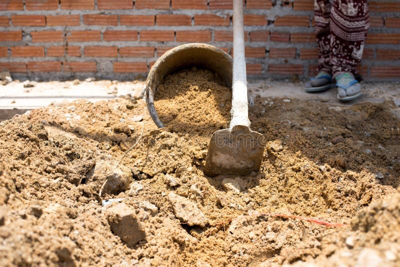 Construction Workers Putting Sand in the Sand Bucket in Building Stock