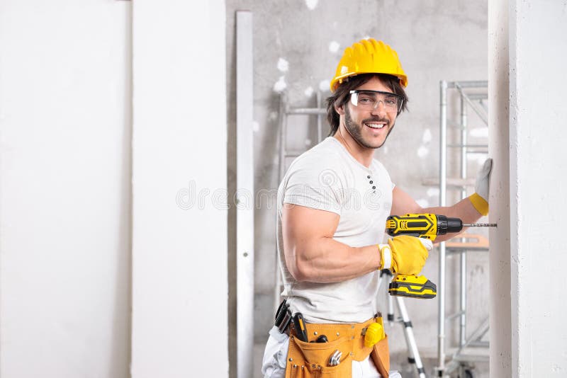 Constructor amigo sonriente trabajando con un taladro imágenes de archivo libres de regalías