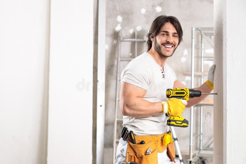 Constructor amigo sonriente trabajando con un taladro foto de archivo libre de regalías