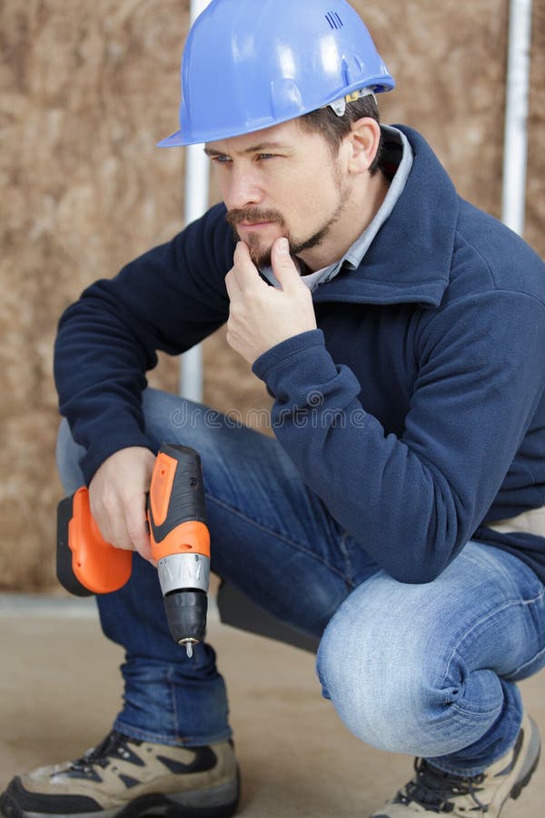 Constructor de hombres pensando dónde perforar imagen de archivo libre de regalías