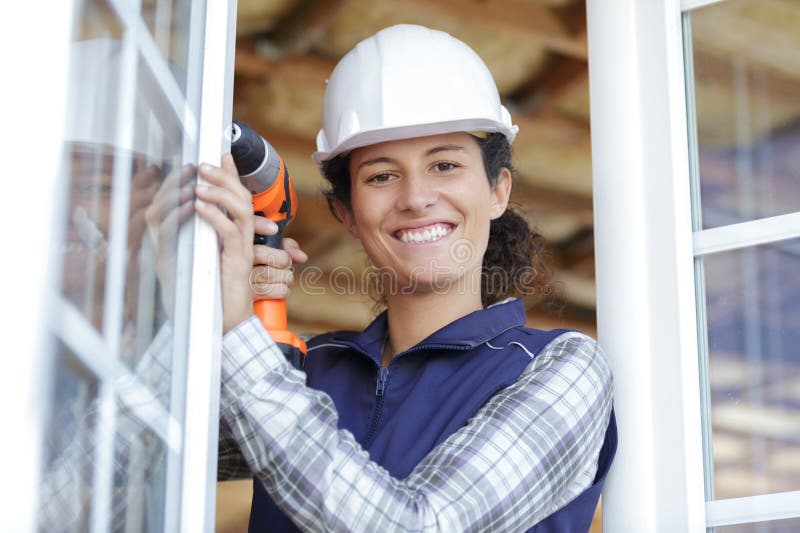 Constructor de mujeres utilizando taladro para la ventana de fijación imágenes de archivo libres de regalías