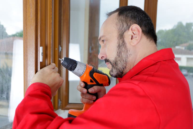 Constructor maduro con perforación en ventanas de madera imagen de archivo libre de regalías