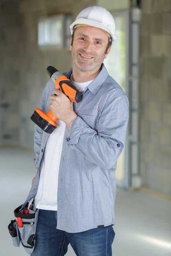 Constructor masculino con taladro naranja inalámbrico fotos de archivo libres de regalías