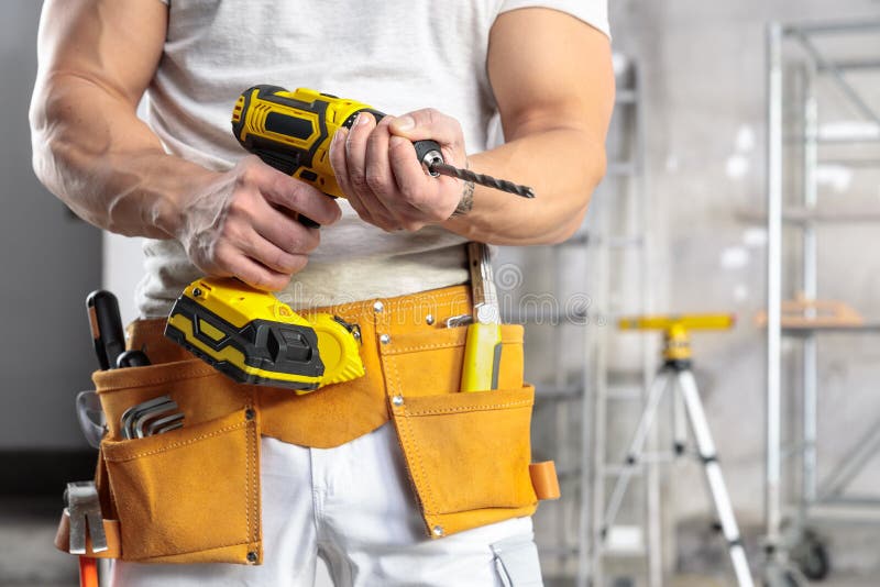 Constructor muscular que sostiene un taladro operado por batería foto de archivo