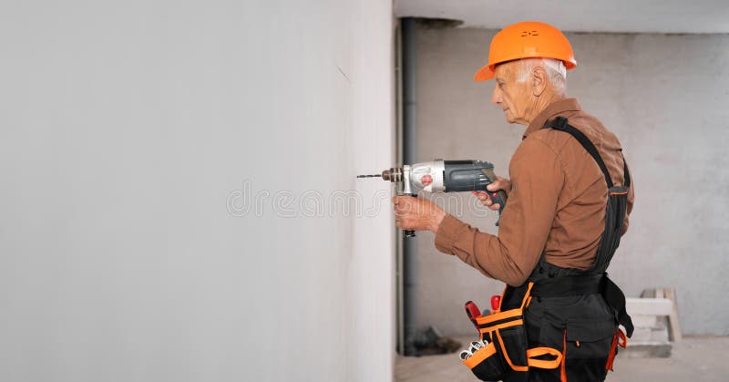 Constructor profesional o hombre de mano en sombrero duro usando un taladro de perforación en la pared imágenes de archivo libres de regalías
