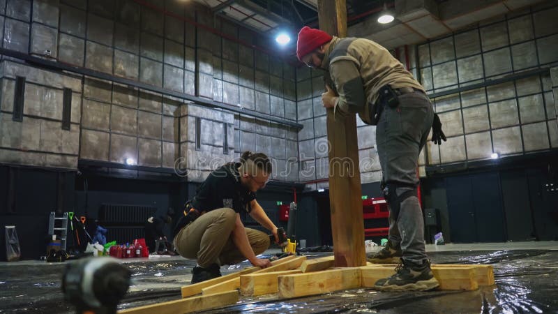 Construção em palco de madeira por jovens construtores. mídia. trabalhadores masculinos que utilizam toros para decoração de