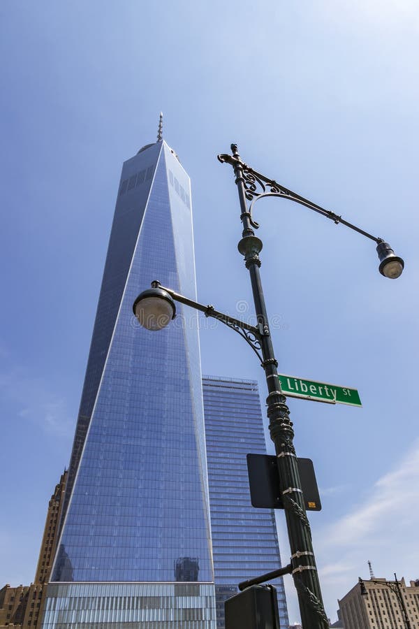 A construção imponente de One World Trade Center com uma luz de rua no primeiro plano com o sinal de rua de Liberty St New York imagens de stock royalty free A construção imponente de One World Trade Center com uma luz de rua no primeiro plano com o sinal de rua de Liberty St New York imagens de stock royalty free