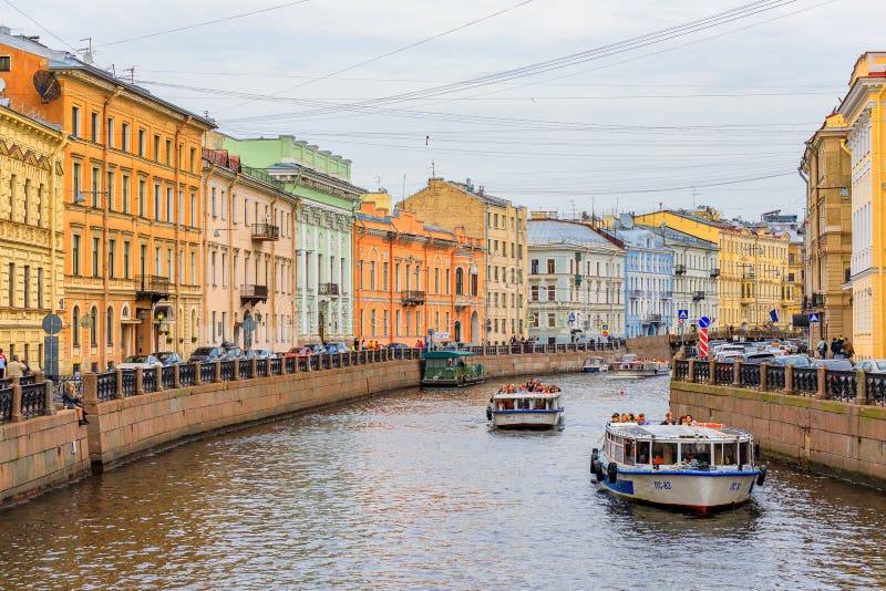 Construções da margem nos bancos do rio Neva e em barcos de turista na água em St Petersburg