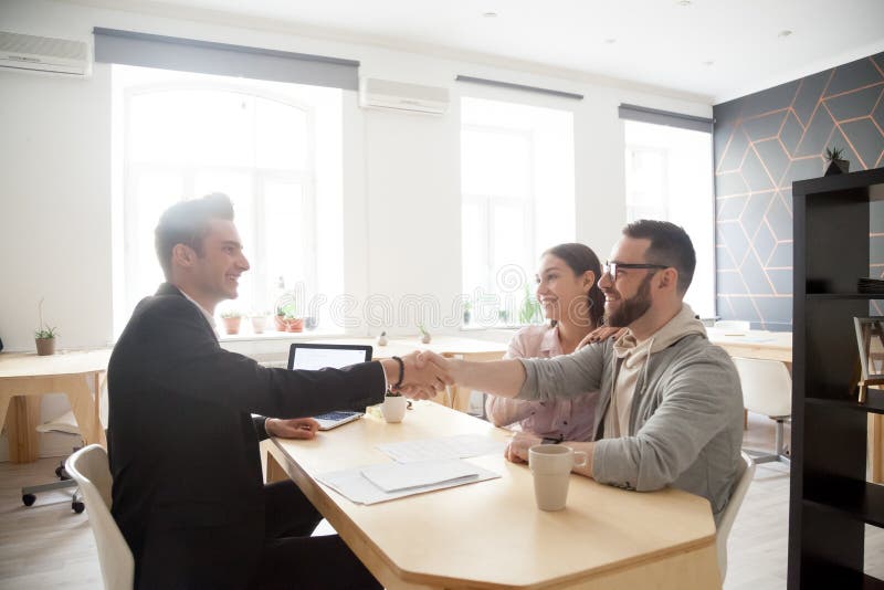 Consulente finanziario sorridente di handshake millenario felice delle coppie, l fotografie stock Consulente finanziario sorridente di handshake millenario felice delle coppie, l fotografie stock
