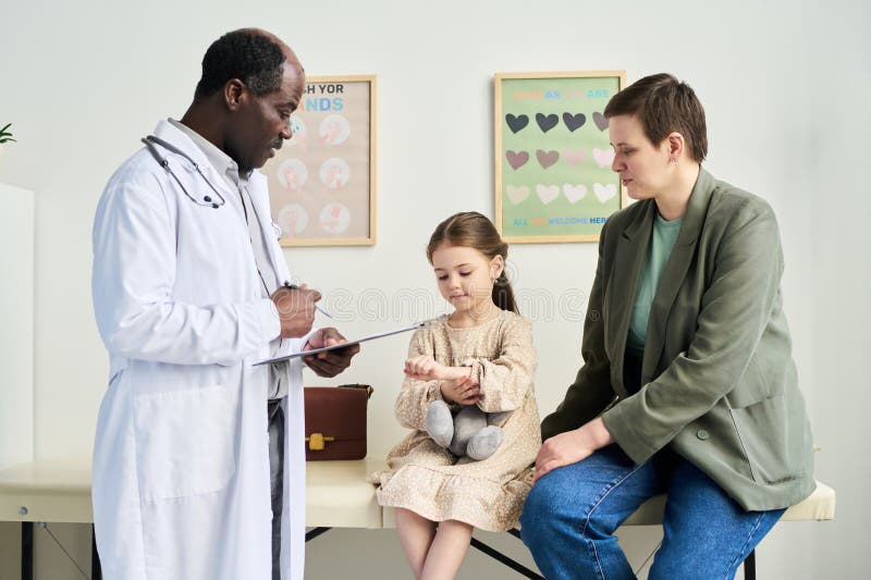 Consulting Doctor with Patient and Parent in Clinical Room stock images