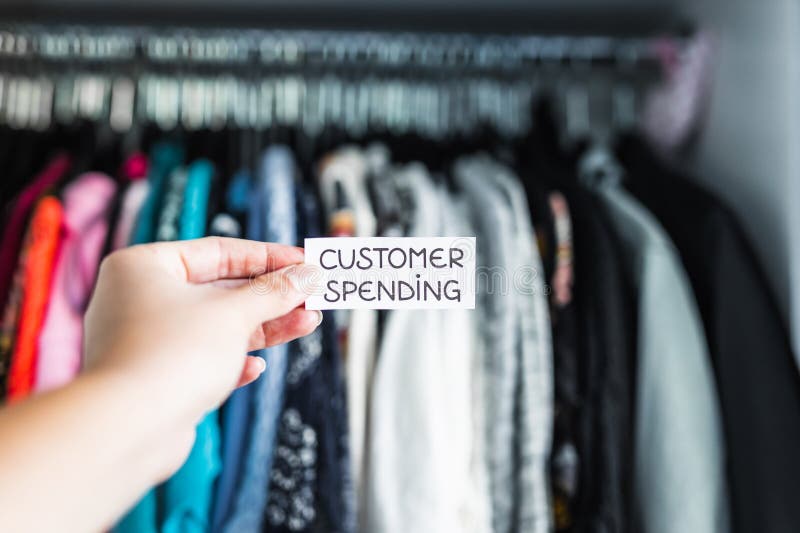 Shopping and consumerism, Consumer Spending sign held in front of wardrobe full of clothes stock photography Shopping and consumerism, Consumer Spending sign held in front of wardrobe full of clothes stock photography