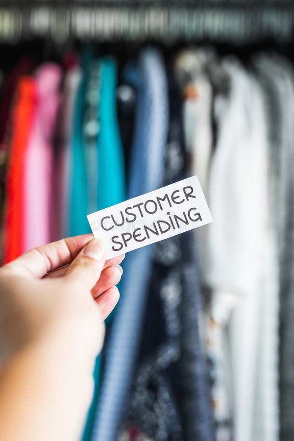 Shopping and consumerism, Consumer Spending sign held in front of wardrobe full of clothes royalty free stock photography Shopping and consumerism, Consumer Spending sign held in front of wardrobe full of clothes royalty free stock photography