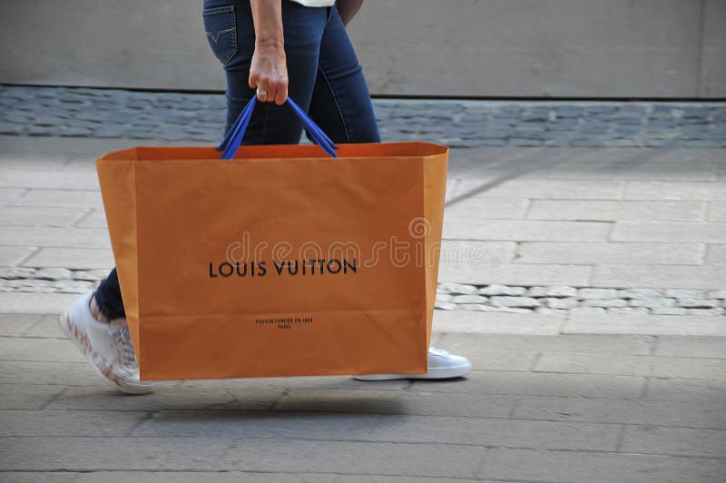 Shoppers in masks wait in line at the Louis Vuitton store in the