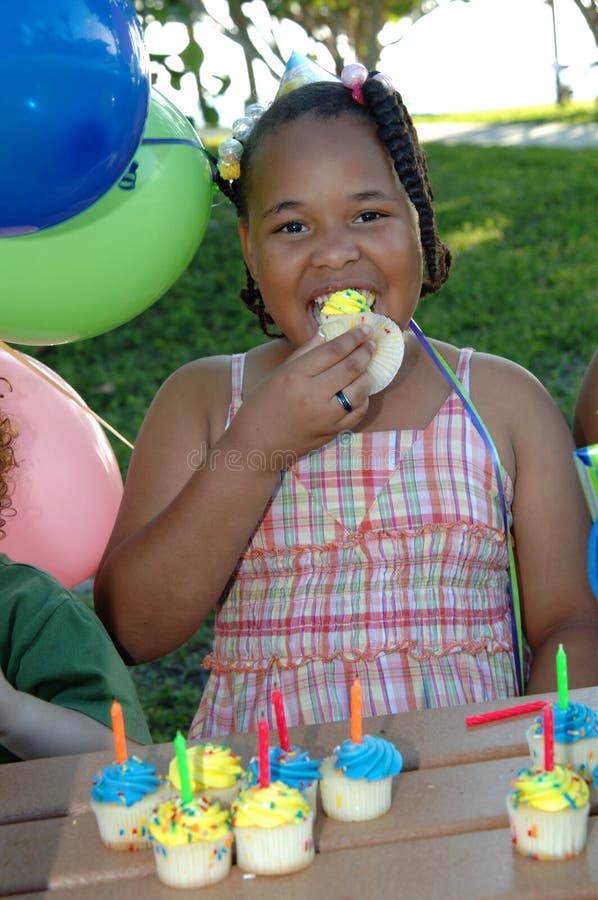 African american girl at a birthday party eating cupcake. African american girl at a birthday party eating cupcake