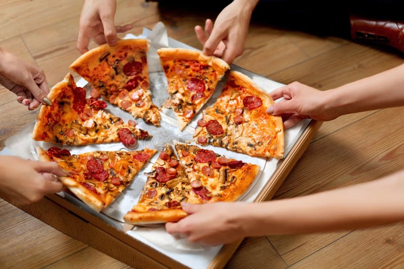 Consumición de la pizza Grupo de amigos que comparten la pizza Alimentos de preparación rápida, ocio