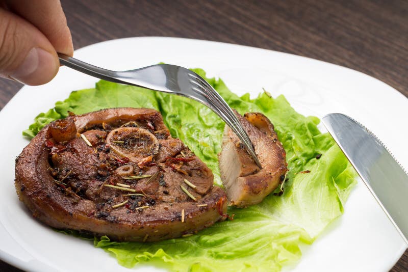 Consumición del filete asado a la parrilla de la carne con la ensalada en la placa blanca fotografía de archivo Consumición del filete asado a la parrilla de la carne con la ensalada en la placa blanca fotografía de archivo