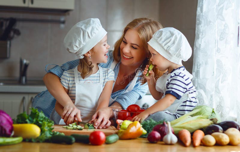Consumición sana La madre y los niños felices de la familia prepara la ensalada vegetal foto de archivo Consumición sana La madre y los niños felices de la familia prepara la ensalada vegetal foto de archivo