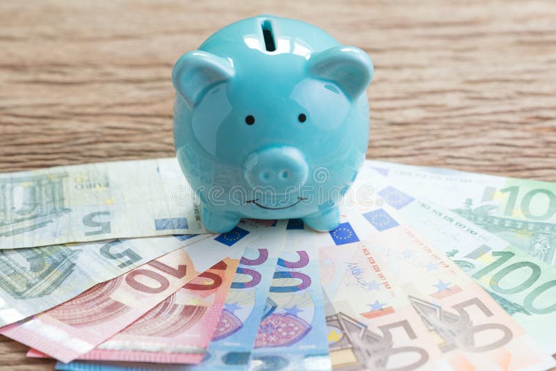 Conta poupança do dinheiro da finança, conceito da economia de Europa, mealheiro azul na pilha de cédulas do Euro na tabela de ma imagens de stock royalty free Conta poupança do dinheiro da finança, conceito da economia de Europa, mealheiro azul na pilha de cédulas do Euro na tabela de ma imagens de stock royalty free