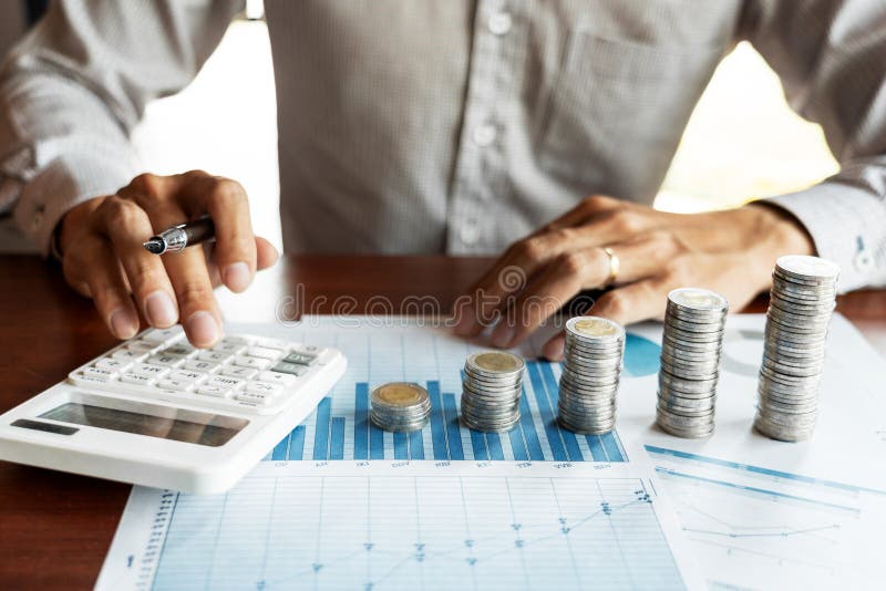 Contador Calculating do homem de negócios em documentos dos dados e em pilha de moedas, o investimento da pilha do dinheiro das e foto de stock royalty free