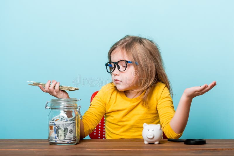 Contador de negócios infantil contando dinheiro e colocando em um banco de jarro ou porquinho. menina fazendo finanças e calculand imagem de stock royalty free