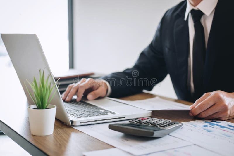Contador do homem de neg? cios que trabalha o projeto novo no laptop com documento do relat? rio e para analisar o gr? fico e o diag fotografia de stock