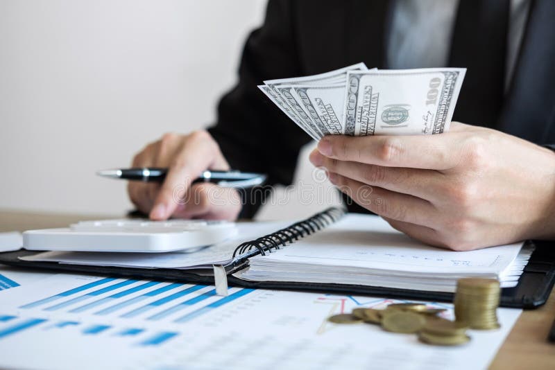 Contador do homem de negócios que conta o dinheiro e que faz anotações no relatório que faz finanças e para calcular sobre o cust imagens de stock