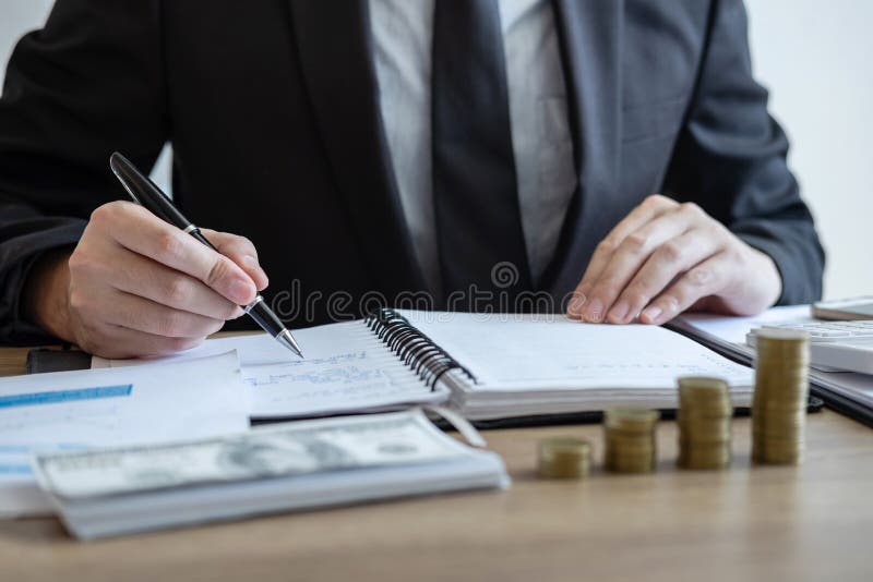 Contador do homem de negócios que conta o dinheiro e que faz anotações no relatório que faz finanças e para calcular sobre o cust fotografia de stock