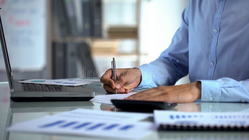 Contador do homem de negócios que usa a calculadora e enchendo o relatório perto do portátil no escritório fotos de stock royalty free