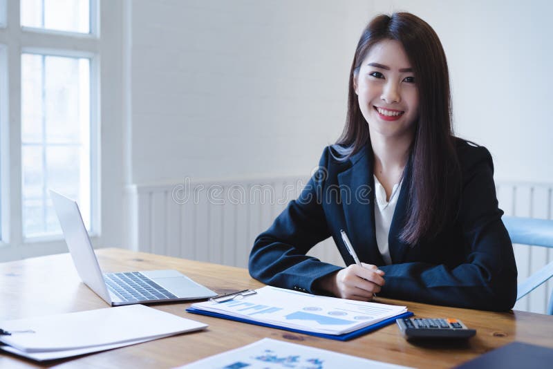 Contador fêmea asiático atrativo que usa a calculadora e discutindo relatórios financeiros Conceito de contabilidade da finança