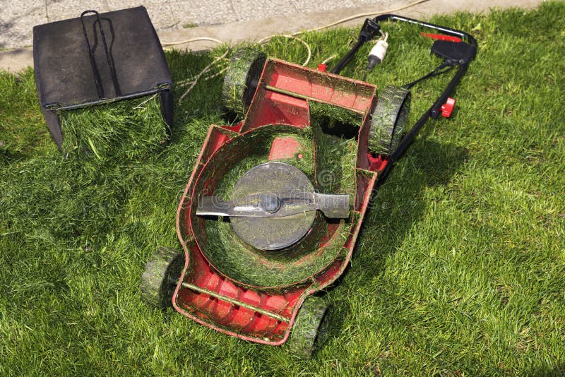Red Lawn Mower Upside Down and Container Full of Grass Stock Image