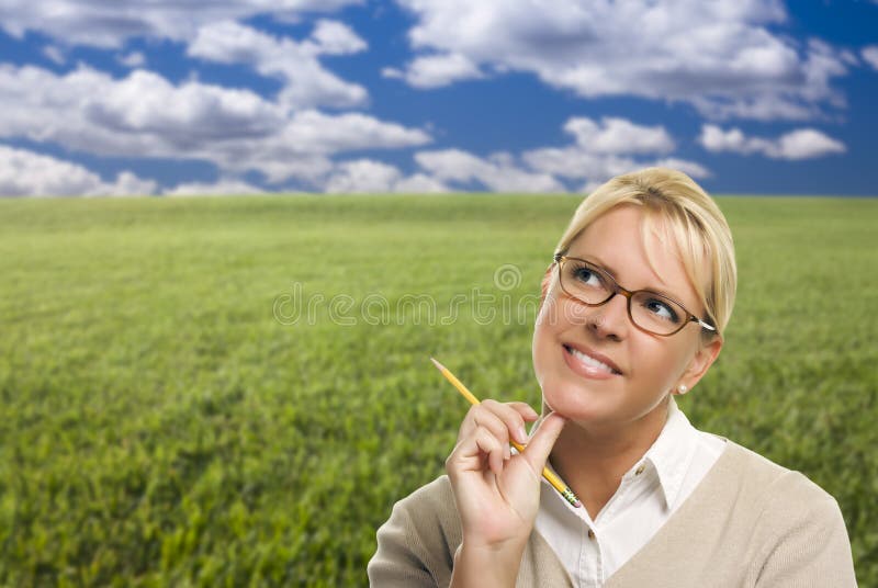 Contemplatieve Vrouw die op Grasgebied kijken op en over stock afbeelding Contemplatieve Vrouw die op Grasgebied kijken op en over stock afbeelding