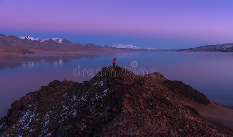 Contemplating Beauty: Mongolia, Alpine Lake Tolbo-Nuur 2079 M., Art Photography.Man In Red Jacket Standing On Red Rock And Photo royalty free stock images Contemplating Beauty: Mongolia, Alpine Lake Tolbo-Nuur 2079 M., Art Photography.Man In Red Jacket Standing On Red Rock And Photo royalty free stock images