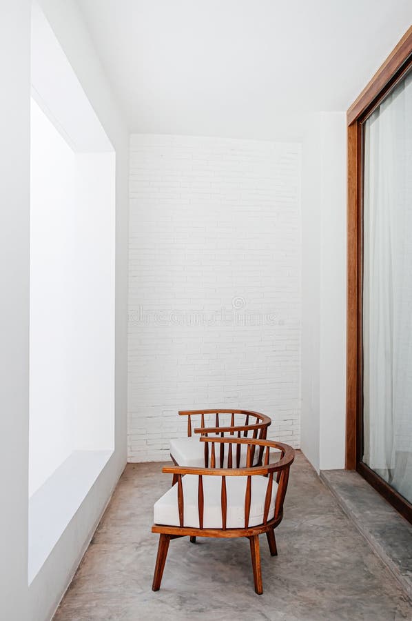 Contemporary wooden chairs at balcony with white concrete brick wall and floor to ceiling window royalty free stock photo Contemporary wooden chairs at balcony with white concrete brick wall and floor to ceiling window royalty free stock photo
