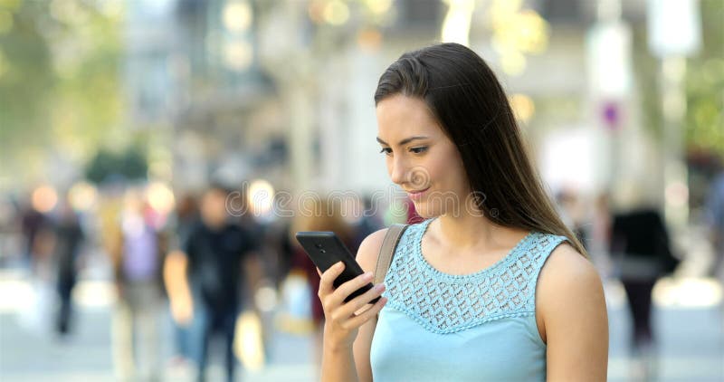 Contenido sorprendido del teléfono de la lectura de la mujer en la calle