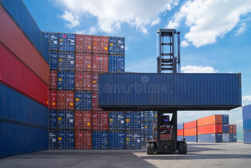 Contenitore di carico di sollevamento del carrello elevatore a forcale nell'iarda di spedizione o nell'iarda del bacino contro il immagini stock libere da diritti Contenitore di carico di sollevamento del carrello elevatore a forcale nell'iarda di spedizione o nell'iarda del bacino contro il immagini stock libere da diritti