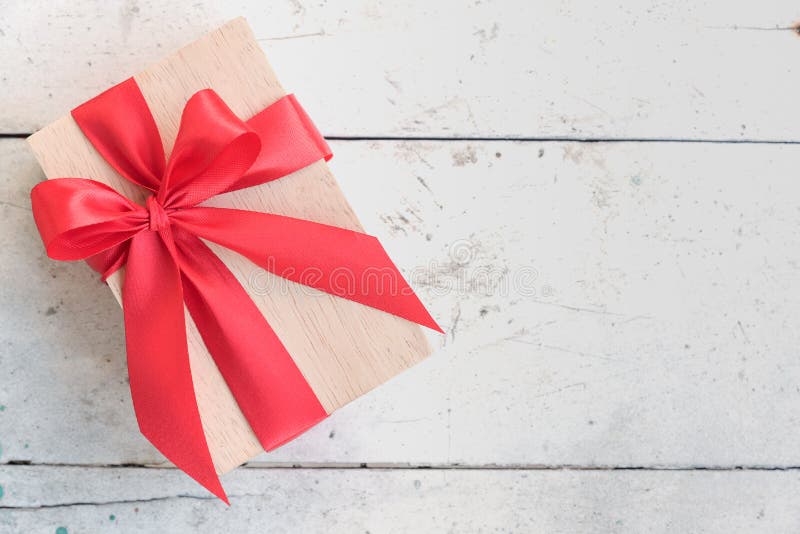Contenitore di regalo di legno con l'arco rosso del nastro su fondo d'annata immagini stock libere da diritti