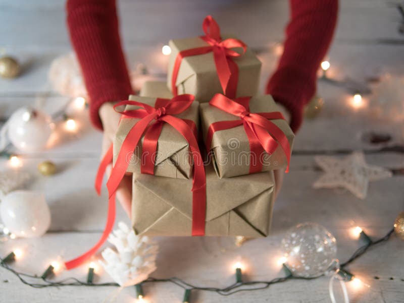 Contenitori di regalo femminili di Natale della tenuta sopra il Natale ornamento e luci fotografie stock libere da diritti Contenitori di regalo femminili di Natale della tenuta sopra il Natale ornamento e luci fotografie stock libere da diritti