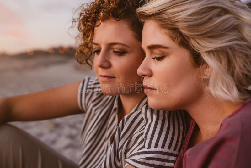 Content Lesbian Couple Wrapped In A Blanket At The Beach Stock Image