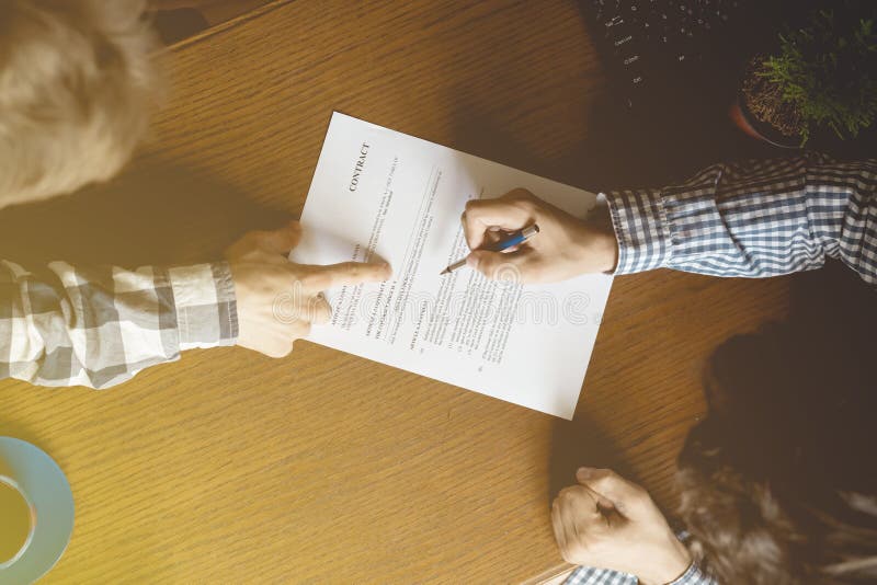 Contract document, two men sign paper in the office a toned faded image