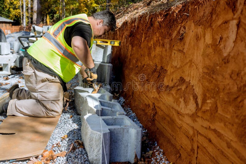 A Contractor is Constructing a Block Retaining Wall on a Construction Site while Installing a