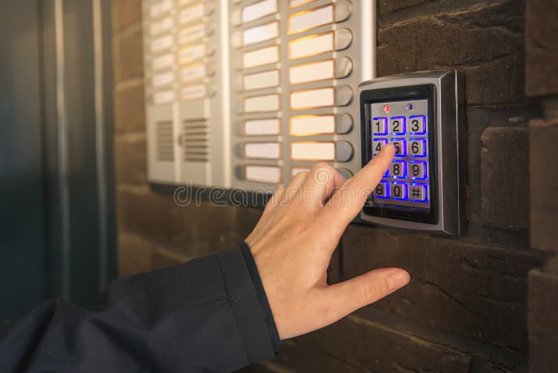 Woman dialing pass code on intercom security keypad to open entrance door of the apartment building. Woman dialing pass code on intercom security keypad to open entrance door of the apartment building.