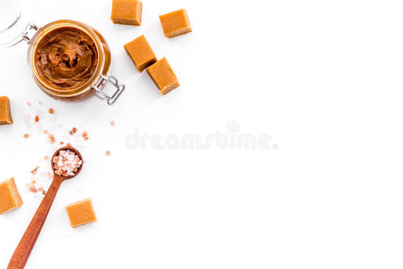 Contrast van aroma's De combinatie zout en zoet Karamelsaus in glaskruik dichtbij karamelkubussen op wit royalty-vrije stock afbeelding Contrast van aroma's De combinatie zout en zoet Karamelsaus in glaskruik dichtbij karamelkubussen op wit royalty-vrije stock afbeelding