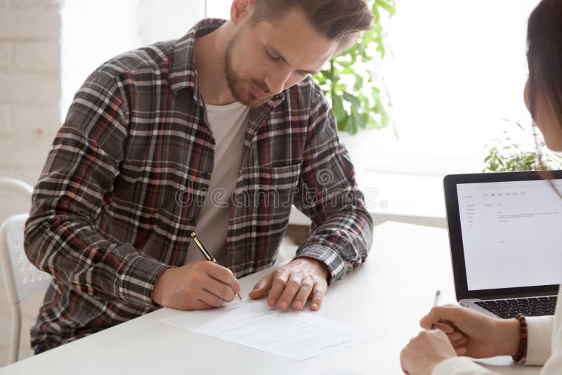 Contrato de trabalho de assinatura focalizado do empregado do sexo masculino após o int bem sucedido imagens de stock Contrato de trabalho de assinatura focalizado do empregado do sexo masculino após o int bem sucedido imagens de stock