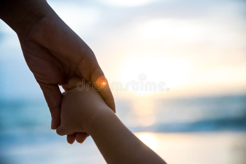 Control suave del padre del foco la mano del pequeño niño durante puesta del sol