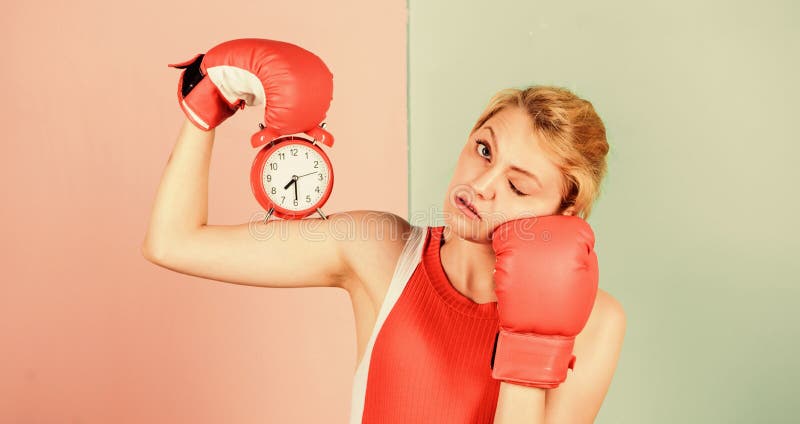 Control time. Time management skills. Battle for self discipline. Woman holding clock boxing gloves. Boxer fighting with alarm clock. Time for boxing training. Punctuality and personal efficiency.