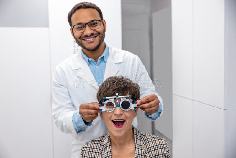 Controllo dell'optometrista maschile alla vista di una visitatrice immagine stock