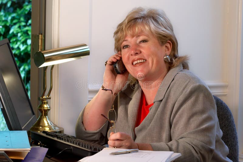 Mature businesswoman laughs during phone conversation. Mature businesswoman laughs during phone conversation